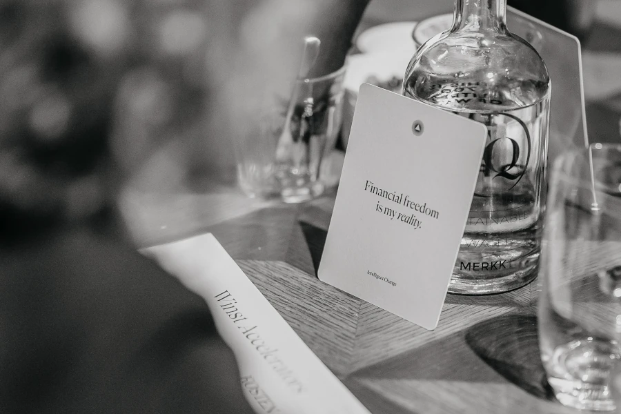 Er staat een fles water op tafel met daar tegen een kaart. Op de kaart staat geschreve, financial freedom is my reality.