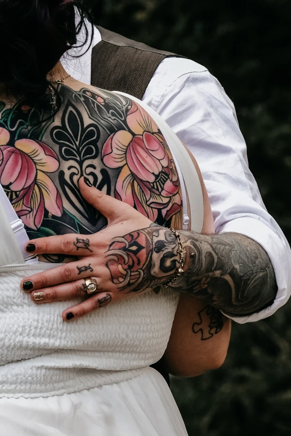 Man legt zijn hand op de rug van de vrouw. Het koppel staat vol tattoo's.